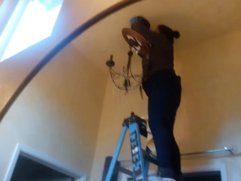 Electrician installing a chandelier in a Fort Mitchell residence